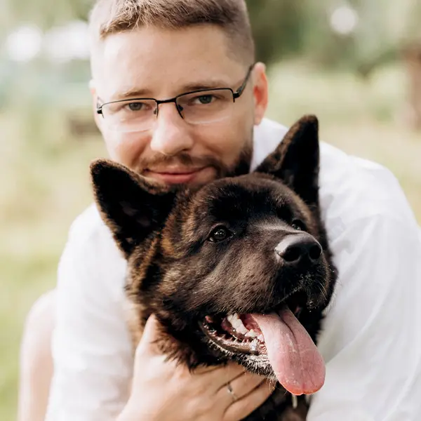 Ein Mann mit Brille umarmt seinen Hund.